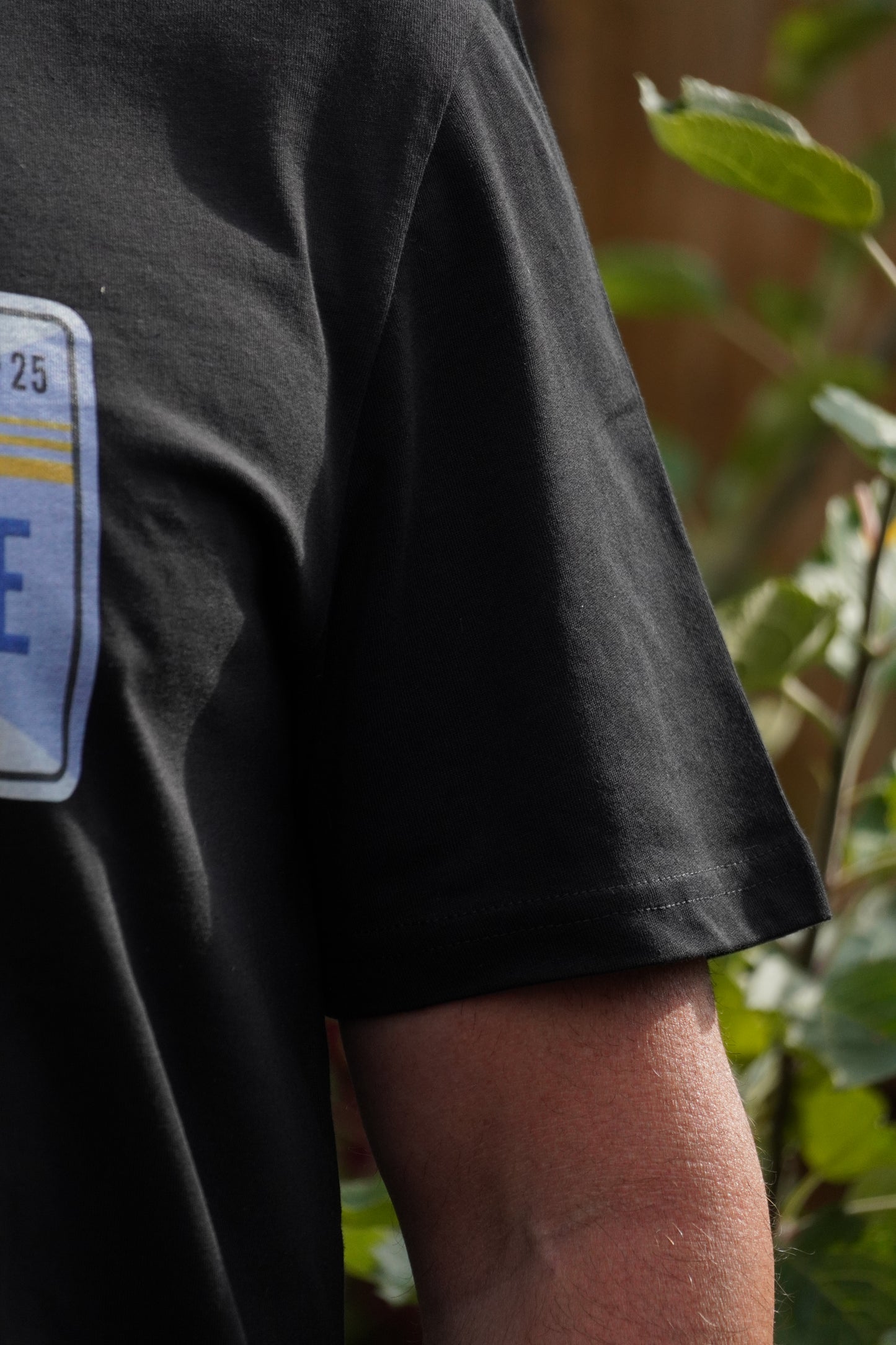 Close-up of Nigel Page wearing short sleeve detail on black Loam Days T-shirt made from 100% organic cotton, featuring cotton blend fabric – mountain biking merch and Innerleithen souvenir inspired by Stay on Your Bike podcast